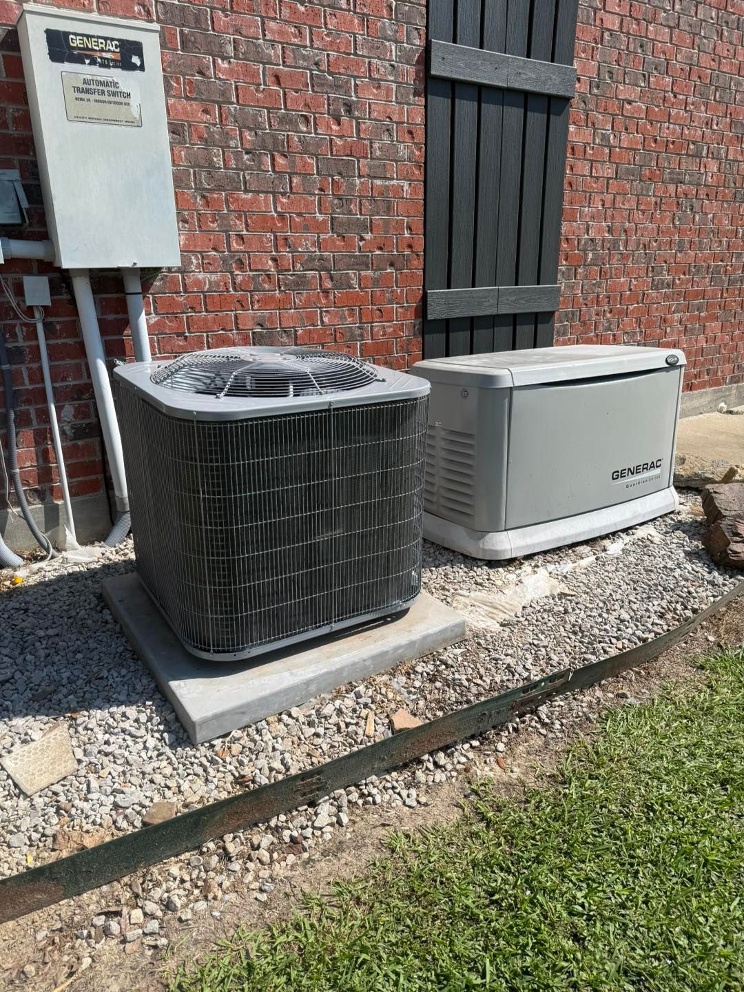 Air conditioner unit and generator beside a brick wall.