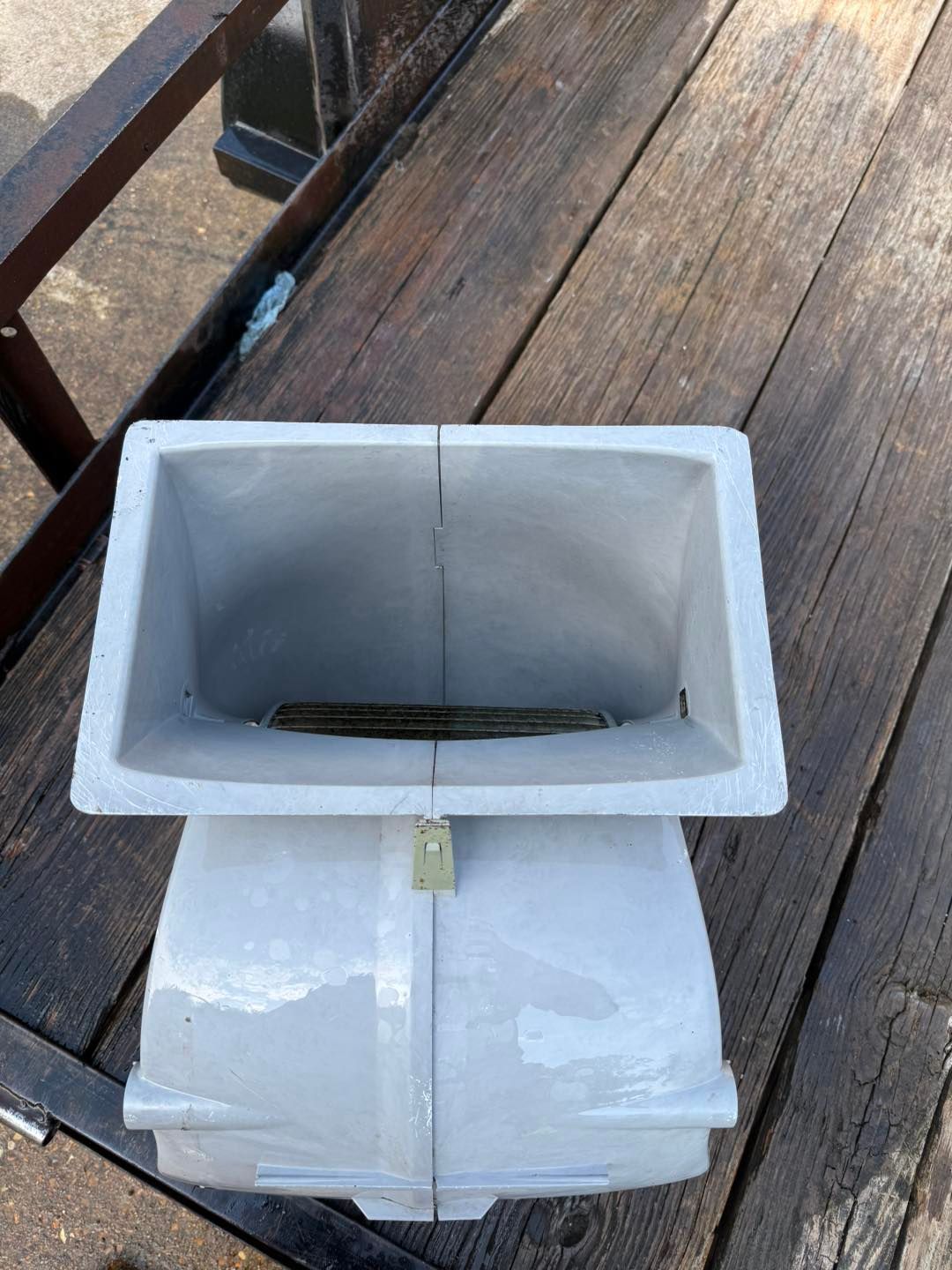 Gray rectangular container with a lock on a wooden surface.
