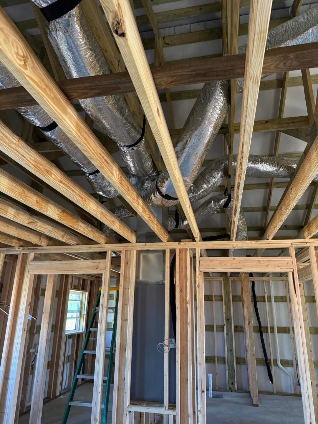 Wooden framing of a room under construction, with exposed ductwork in the ceiling.