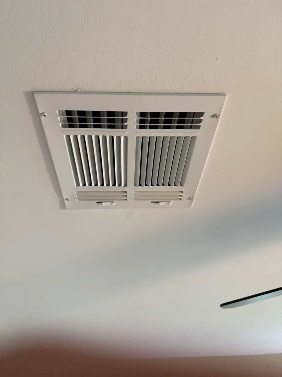White ceiling vent with vertical slats.