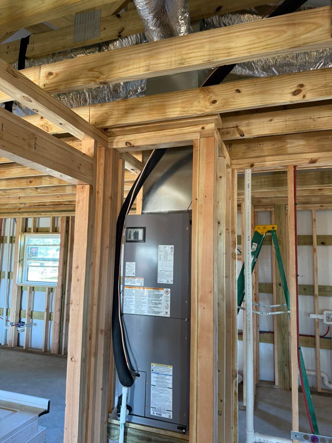 New construction: HVAC unit installed within a wooden frame, ductwork above.