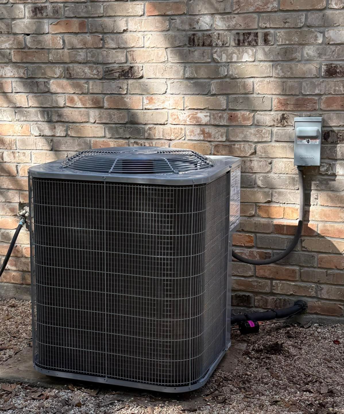 Outdoor air conditioning unit against a brick wall.
