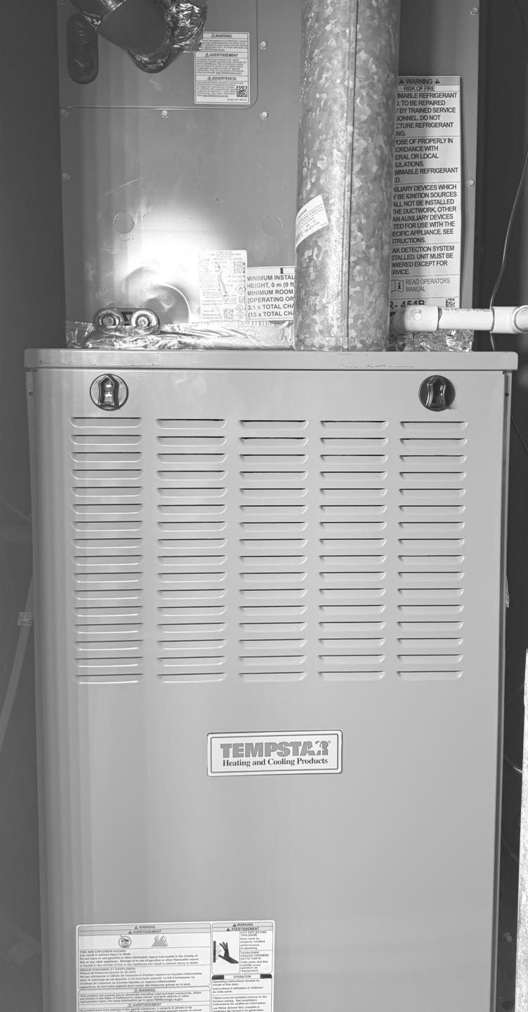 Gas furnace with vent pipes and access panel, indoors.