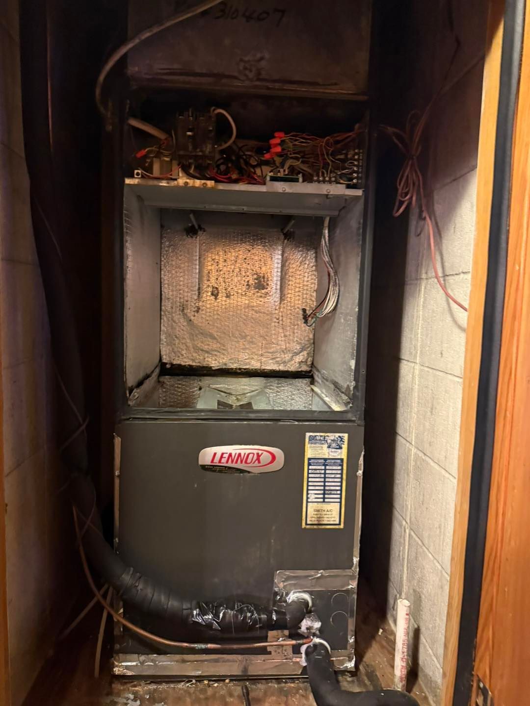 Furnace unit in a utility closet with ductwork and wiring visible.