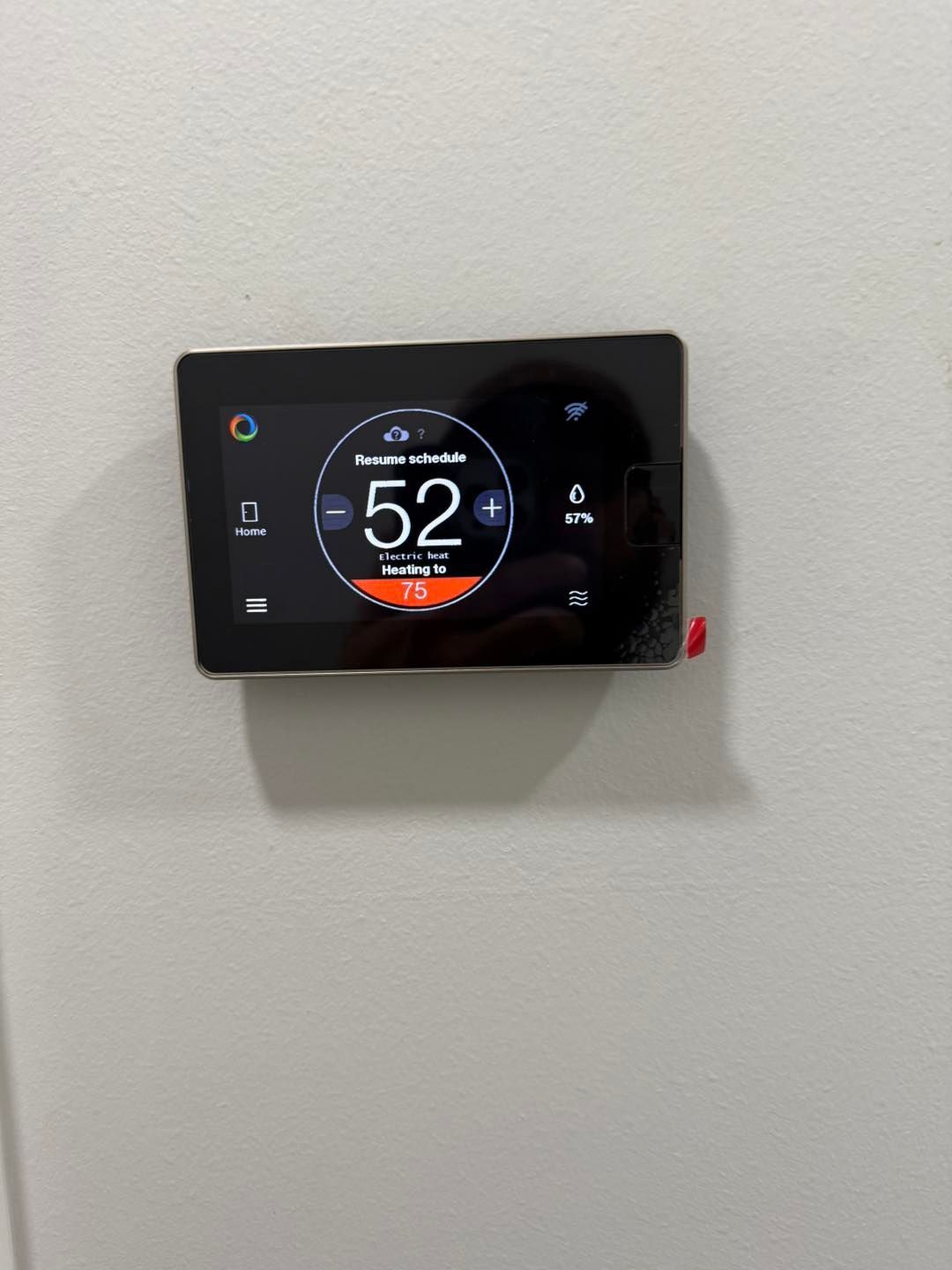 Thermostat showing a temperature of 52 degrees. The set temperature is 75 degrees. The screen is black with white and orange text.
