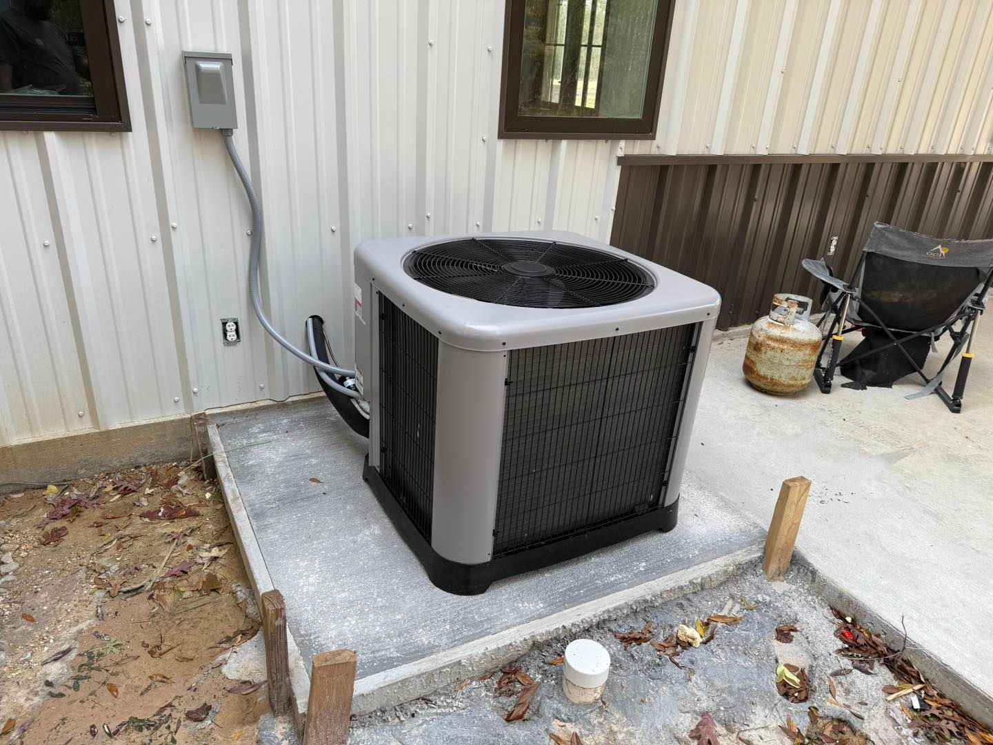 Air conditioning unit on a concrete pad next to a building.