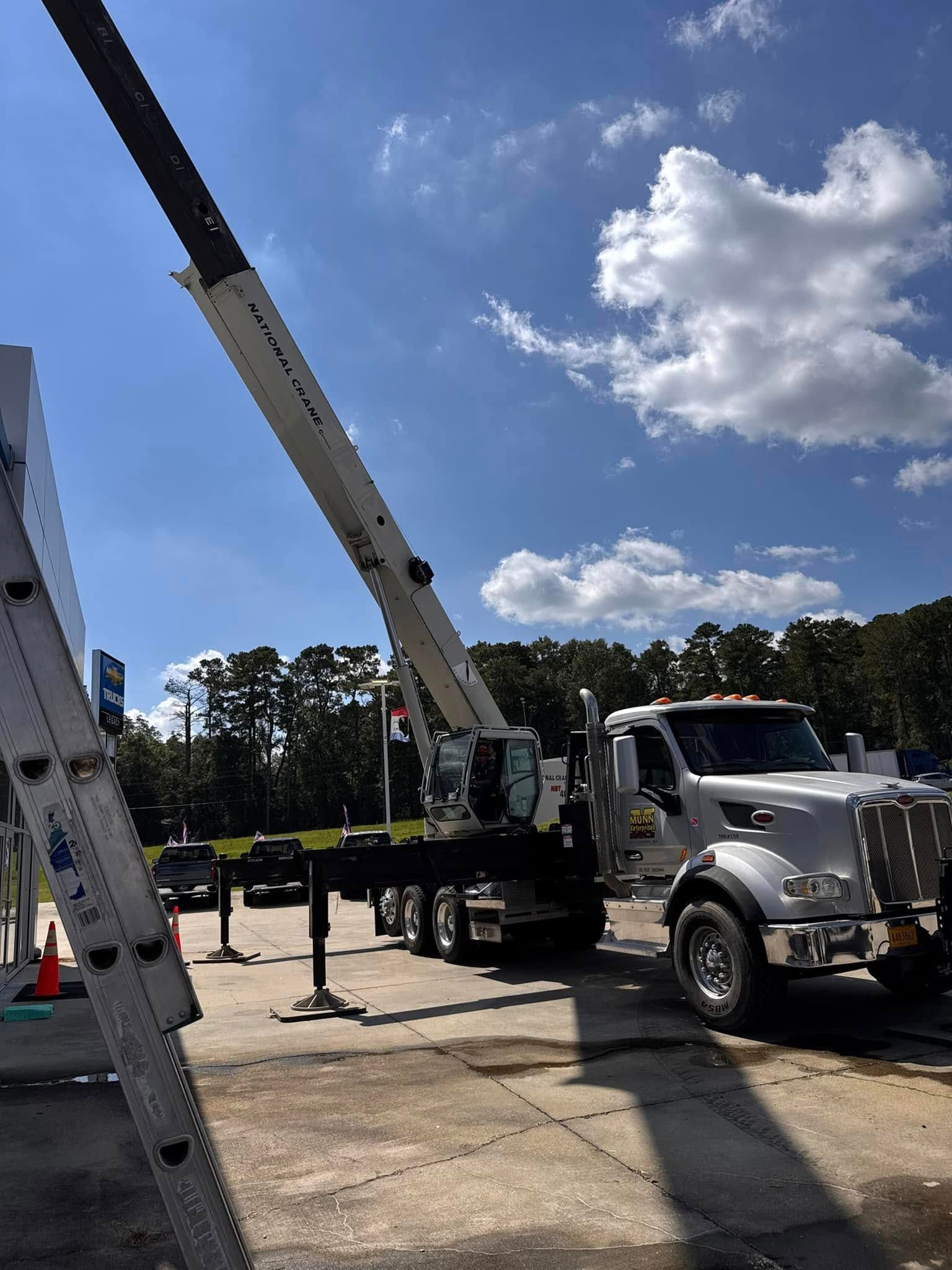 White utility truck with extended boom lift in a sunny outdoor lot under a blue sky