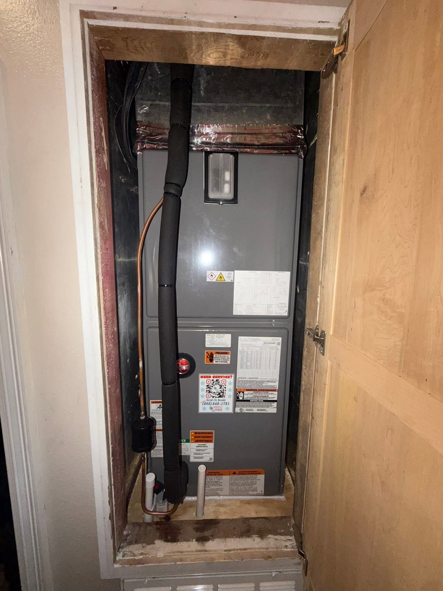 Open electrical panel in a wall alcove with exposed wiring and labels.