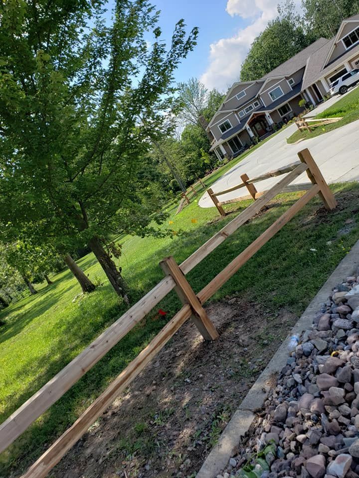 Wooden fence under construction in a grassy suburban yard beside a gravel path and townhouses.