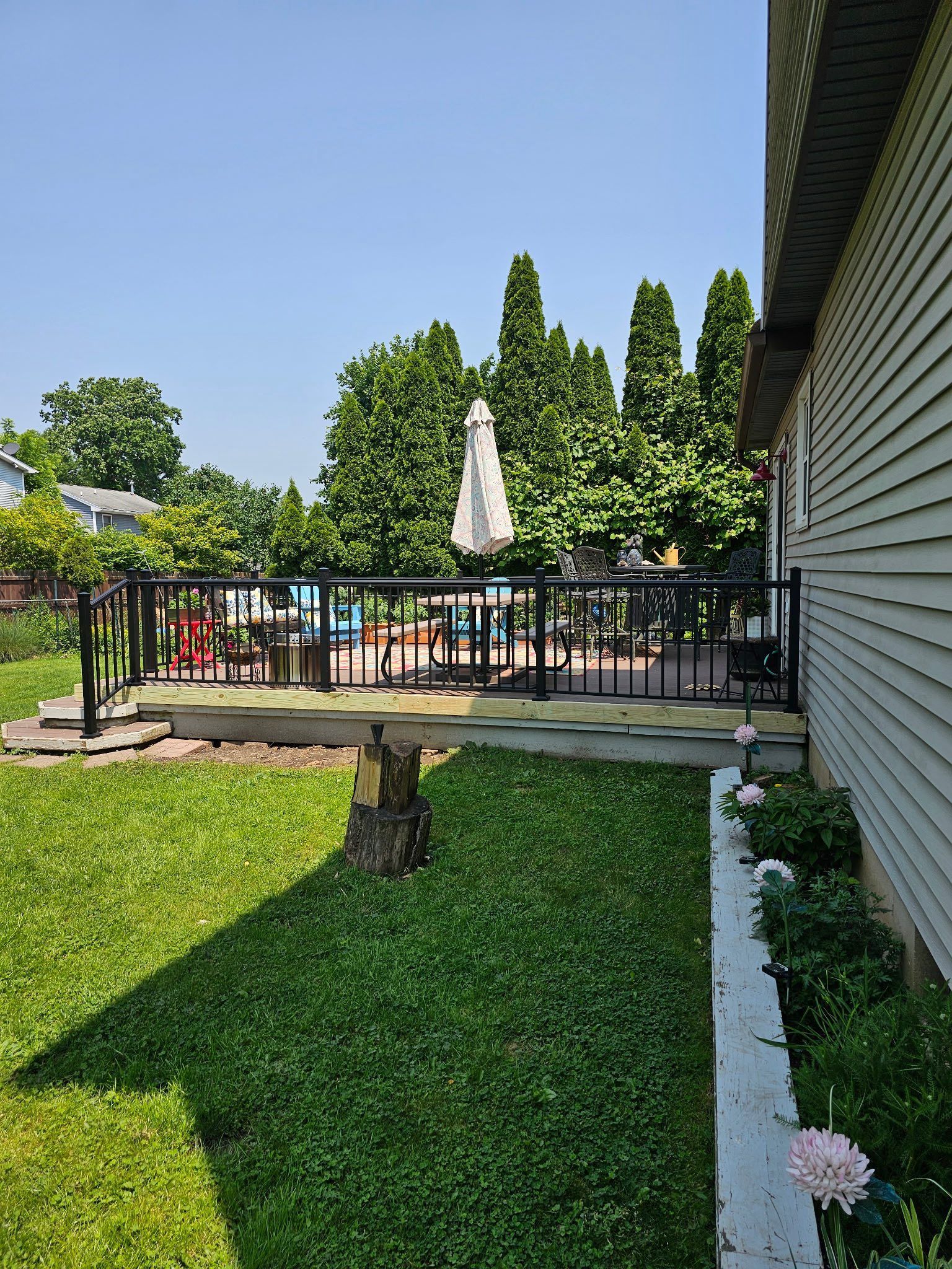 Outdoor poolside patio with umbrella tables, green lawn, and a building wall on the right