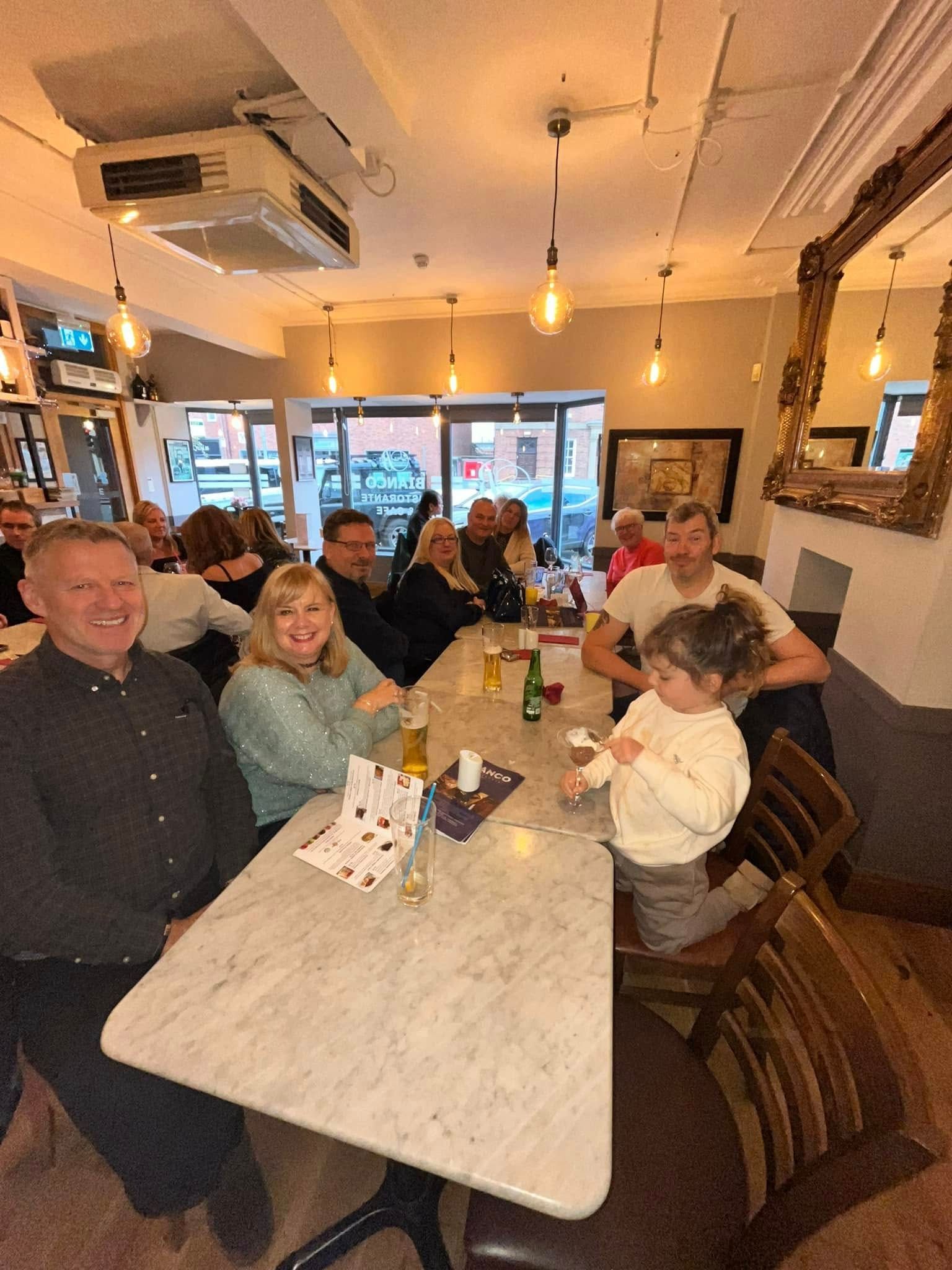 A group of people sitting at a table in a pub or restaurant, smiling and socializing.