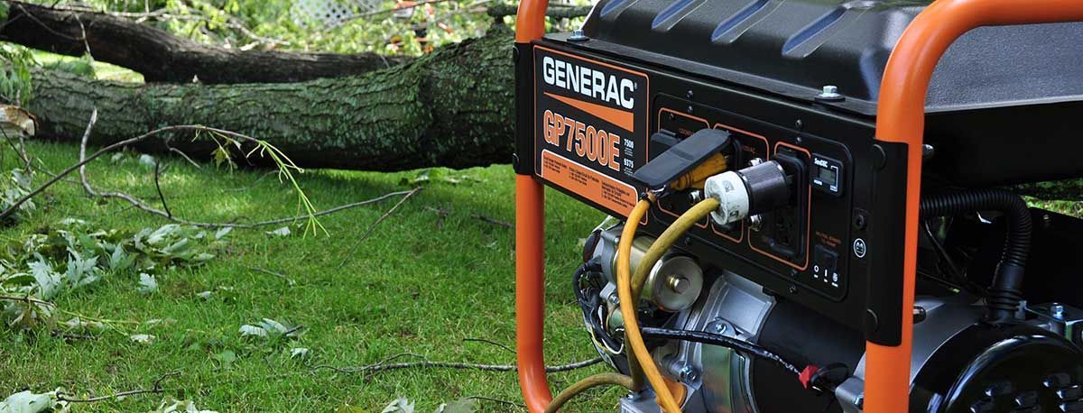A generator is sitting in the grass next to a tree.