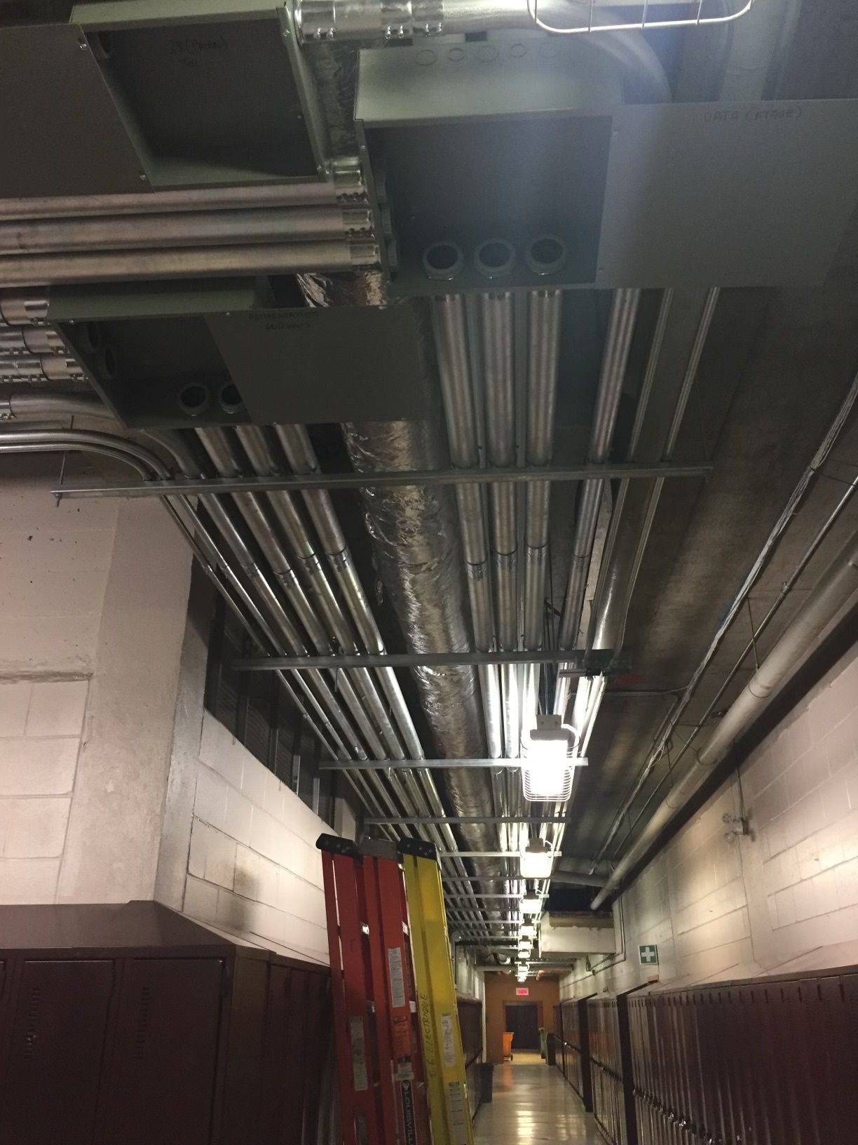 Un long couloir avec beaucoup de tuyaux suspendus au plafond.