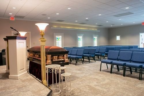 Funeral chapel with casket, podium, and rows of blue chairs