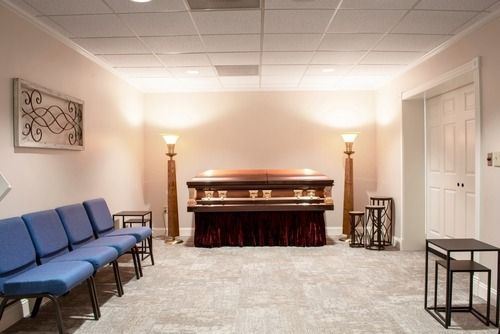 Small funeral chapel with casket, blue chairs, and soft lighting