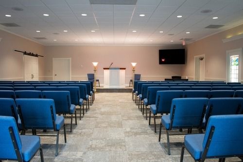 Empty chapel with rows of blue chairs facing a small altar at the front