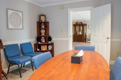 Conference room with orange table, blue chairs, and open doors to a hallway and cabinet