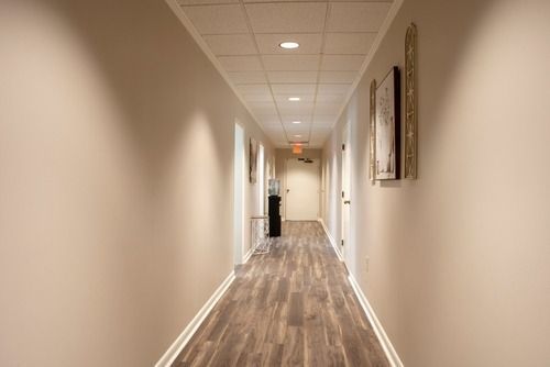 Long, narrow beige hallway with wood flooring and framed wall art