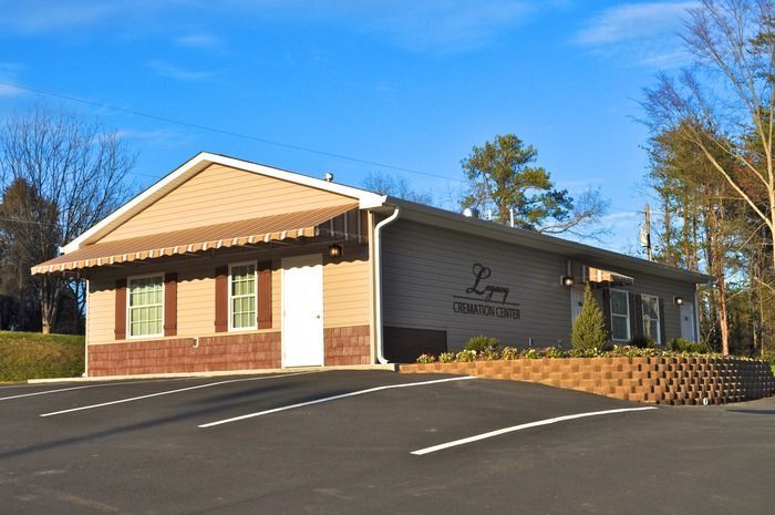 Single-story brick office building with beige siding and parking lot under a clear blue sky