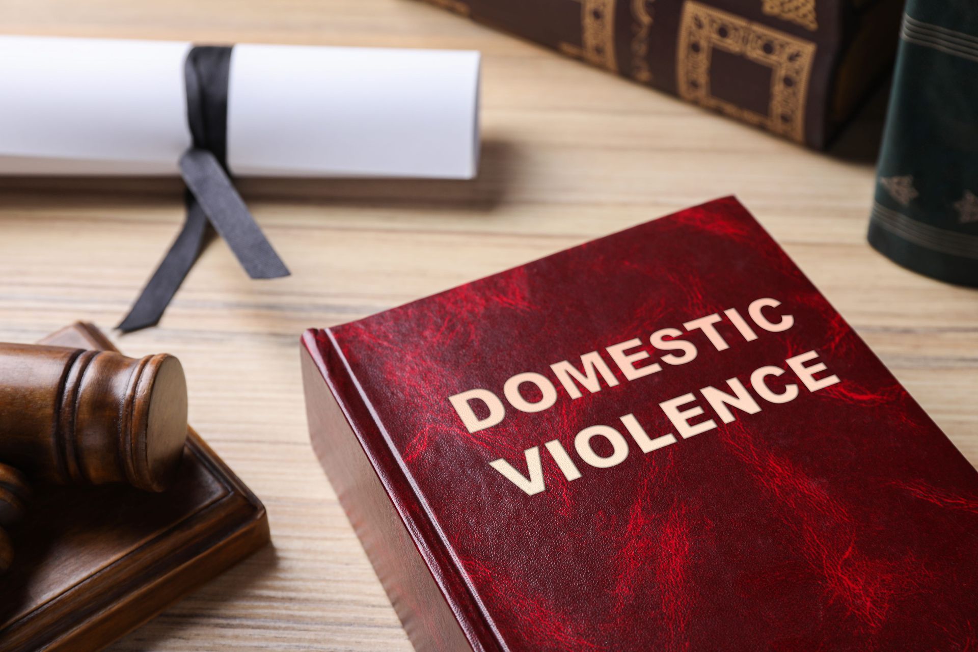 Domestic violence law book beside a judge’s gavel and diploma scroll on a desk