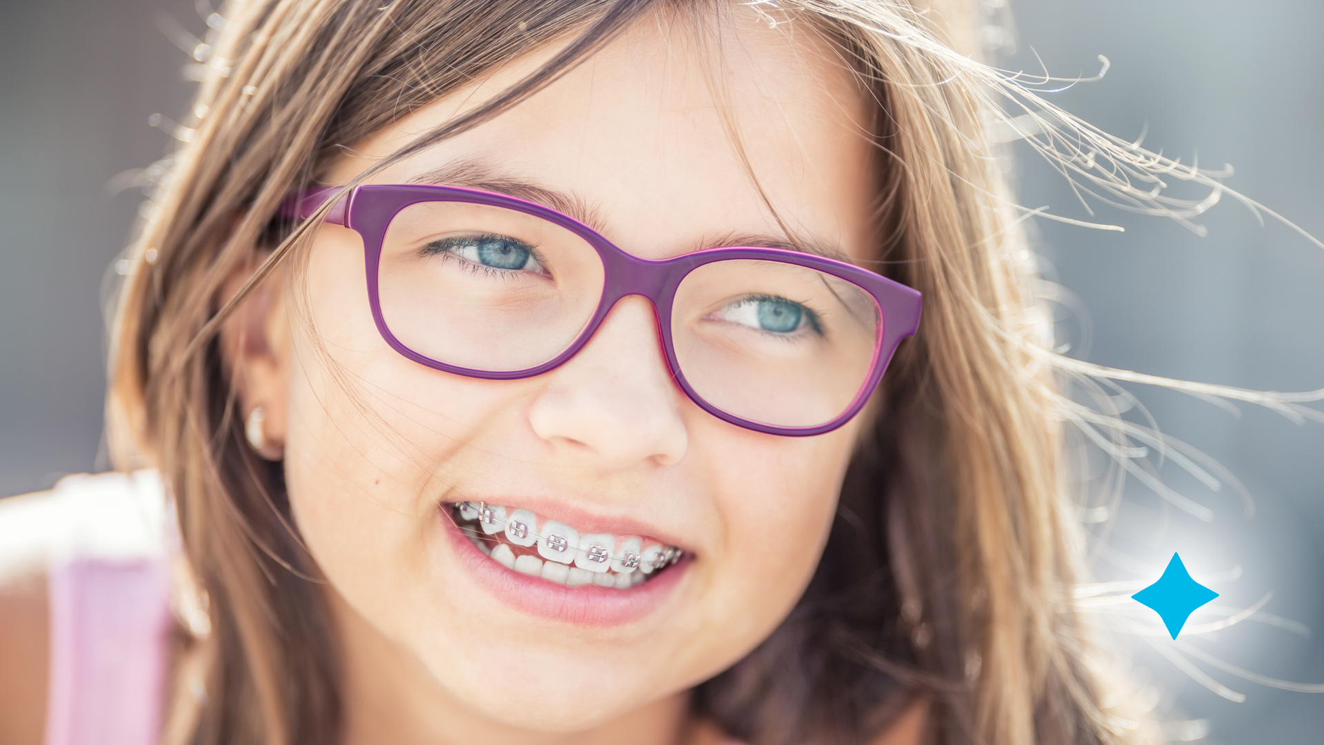 A young girl wearing glasses and braces is smiling for the camera.