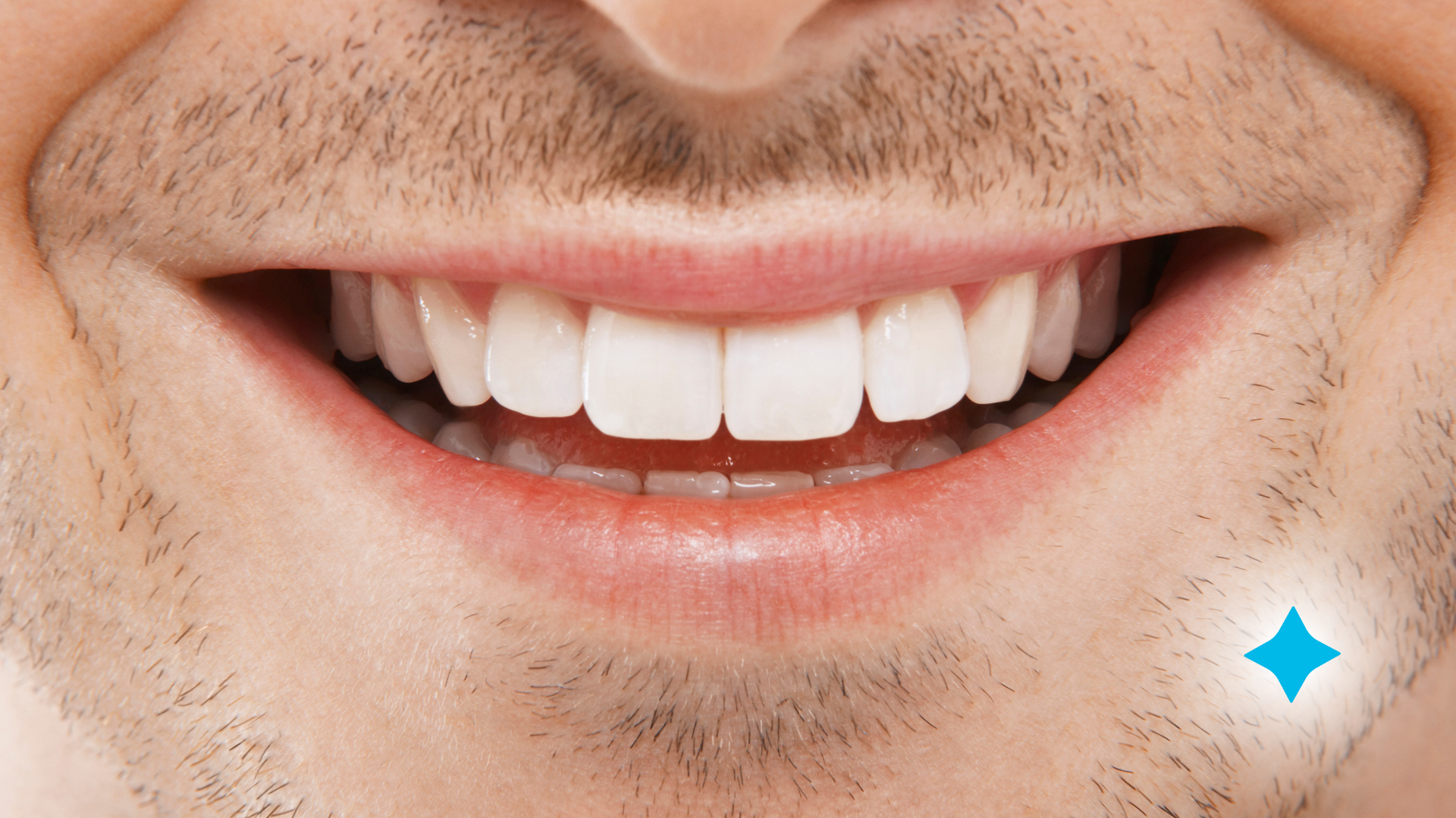 A close up of a man 's mouth with white teeth and a beard.