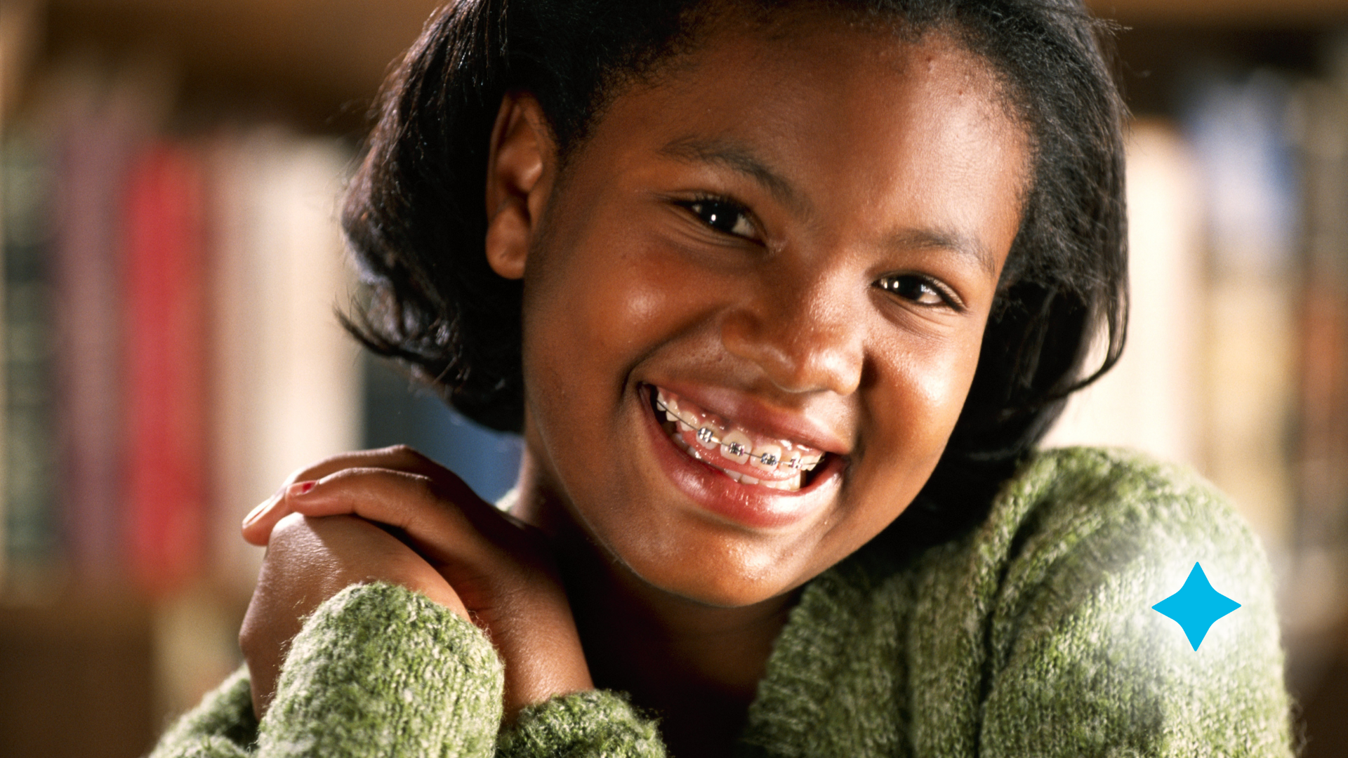 A young girl with braces on her teeth is smiling for the camera.
