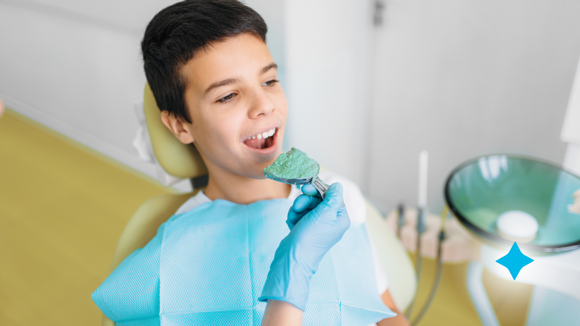 A young boy is sitting in a dental chair eating a piece of food.