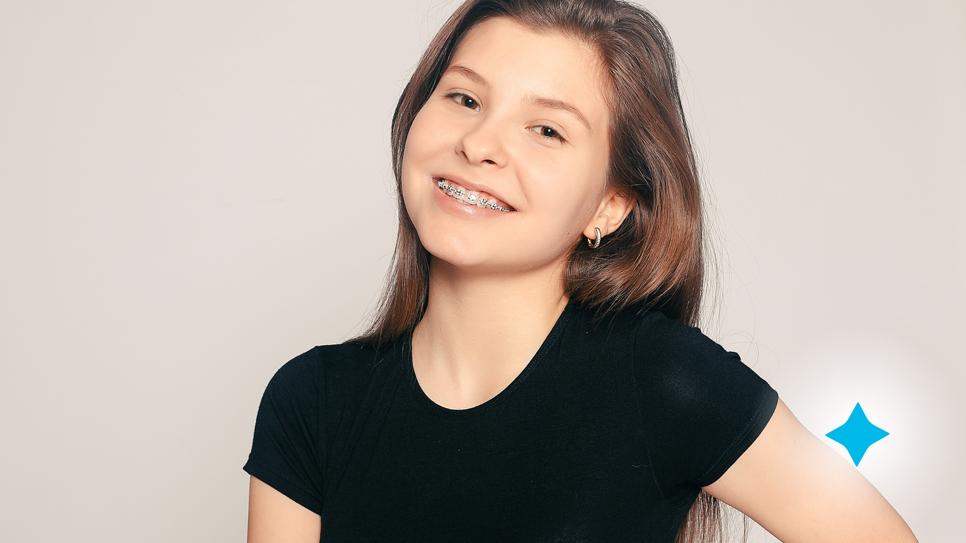 A young girl with braces on her teeth is wearing a black shirt and smiling.