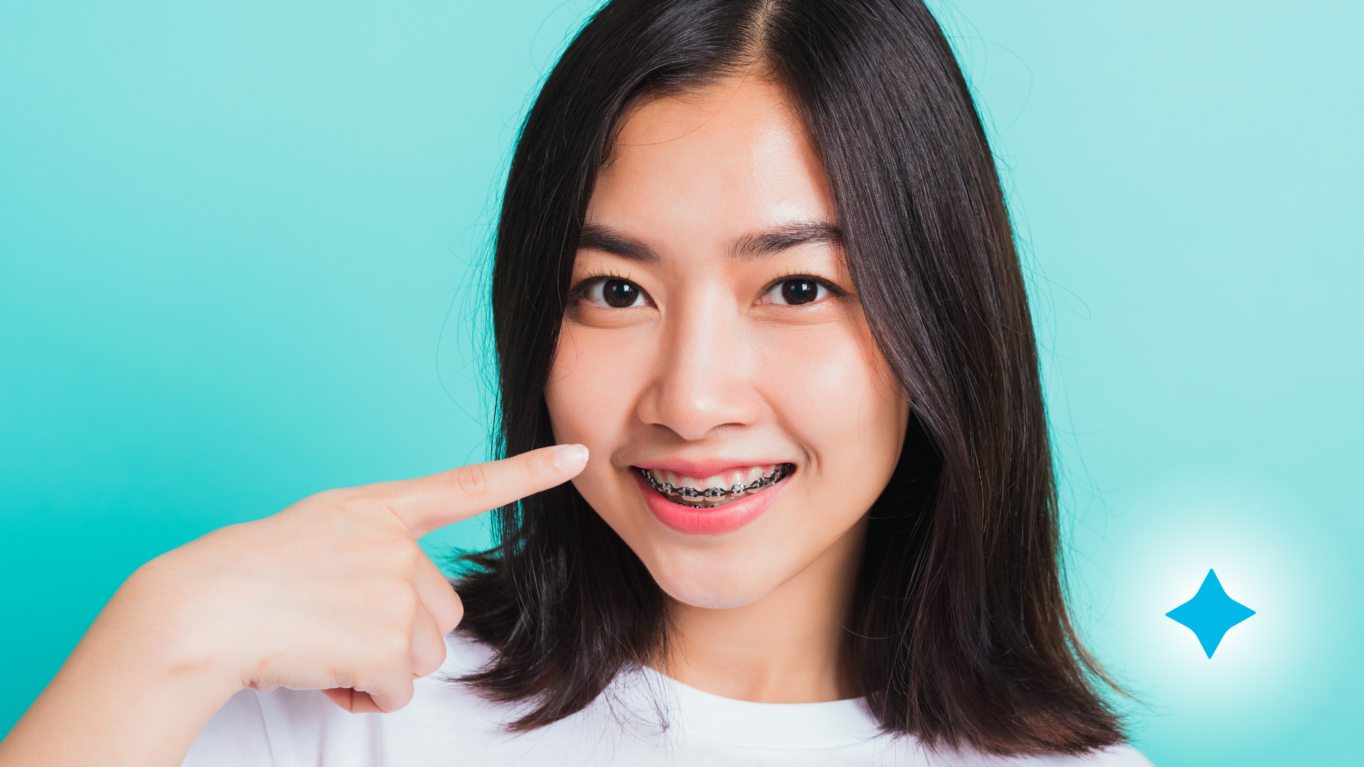 A woman with braces is pointing at her teeth.