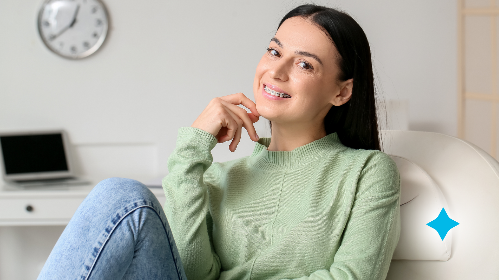 A woman is sitting on a couch with her legs crossed and smiling.
