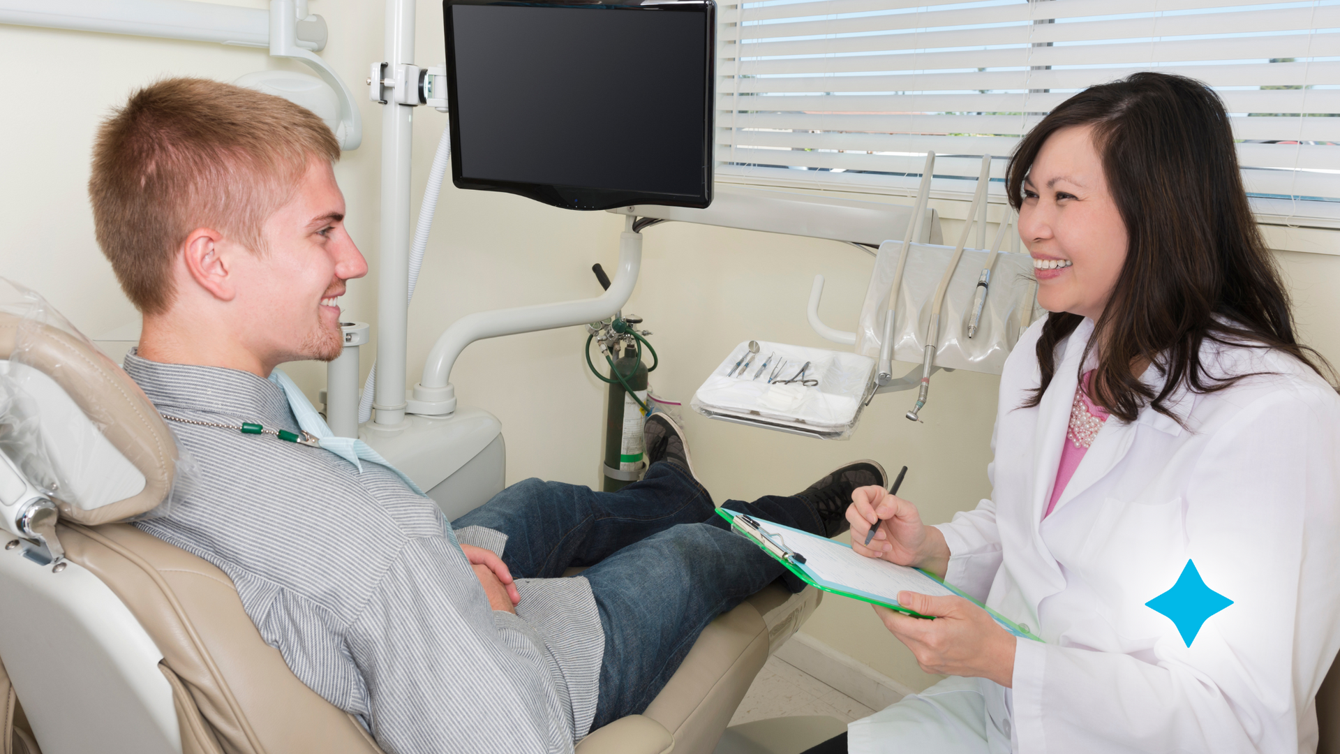 An orthodontist is talking to a patient in a dental chair.