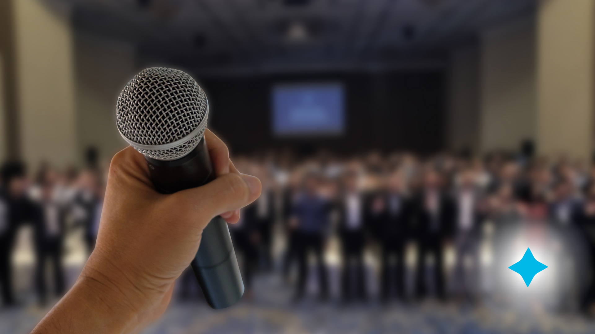 A person is holding a microphone in front of a crowd.