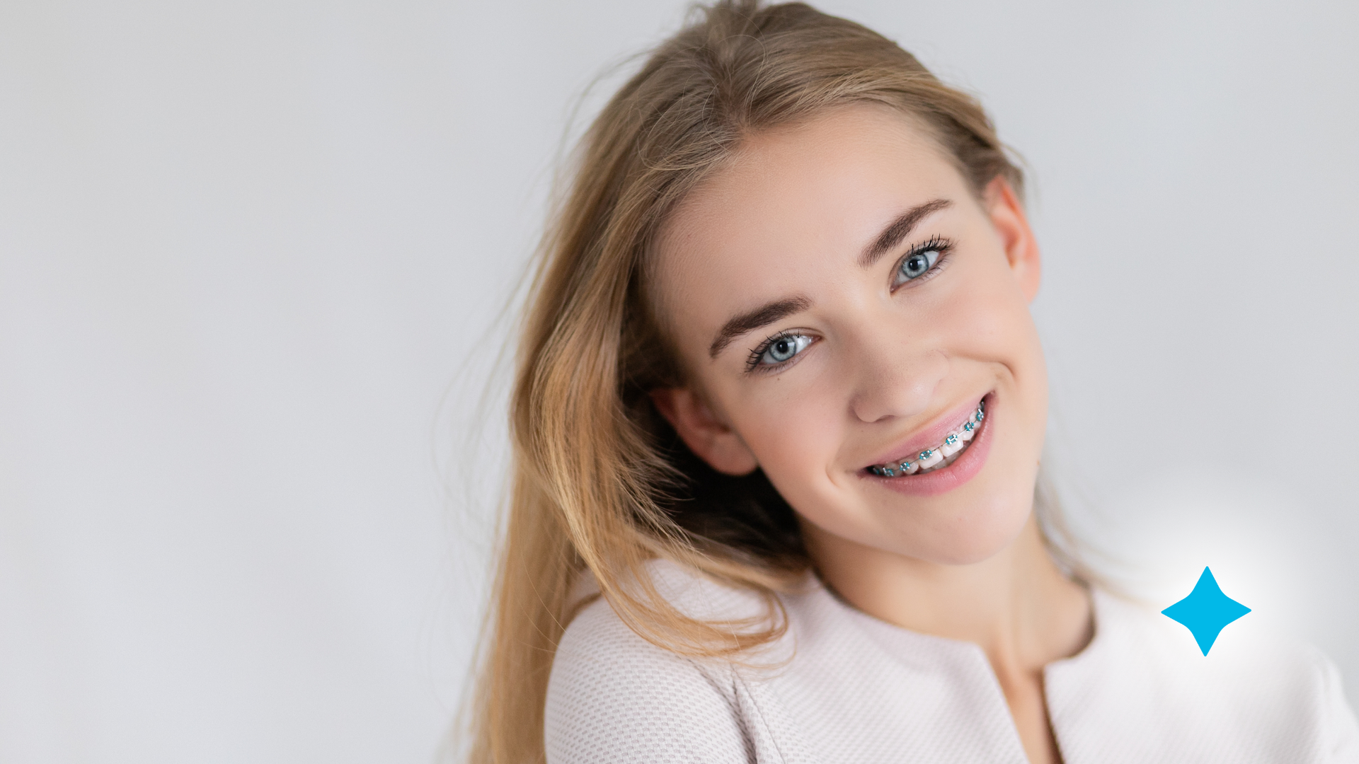 A young girl with braces on her teeth is smiling for the camera.