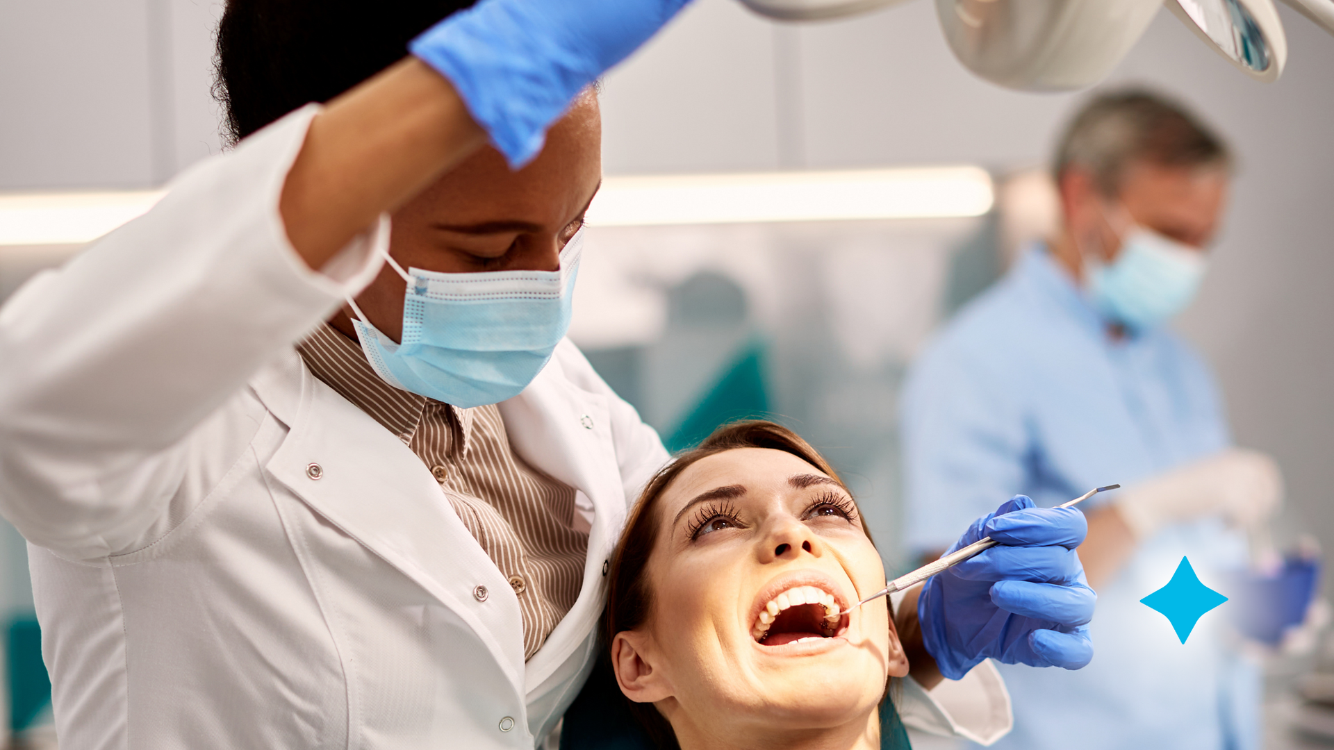A woman is sitting in a dental chair while an orthodontist examines her teeth.