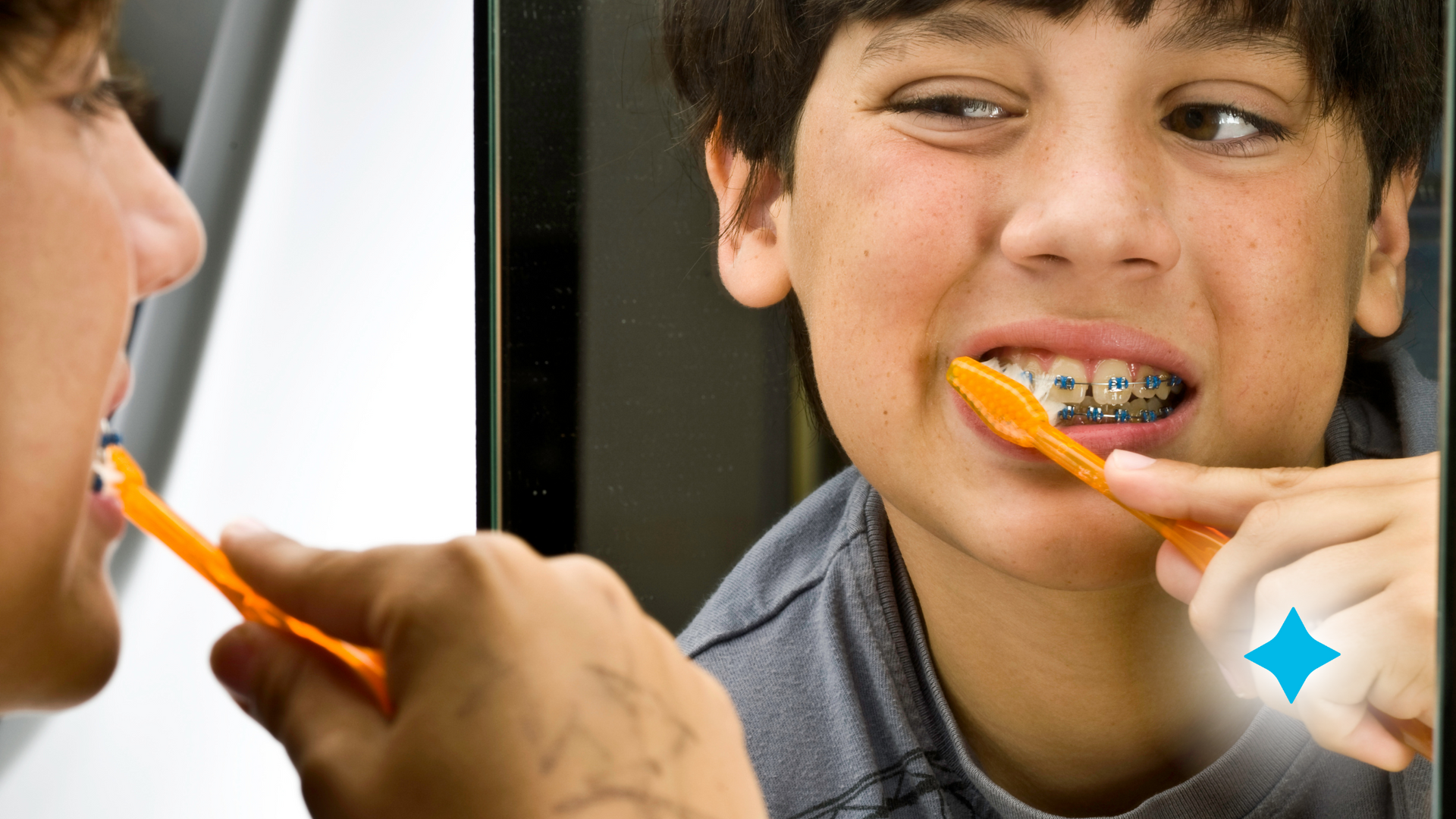 A boy with braces is brushing his teeth in front of a mirror.