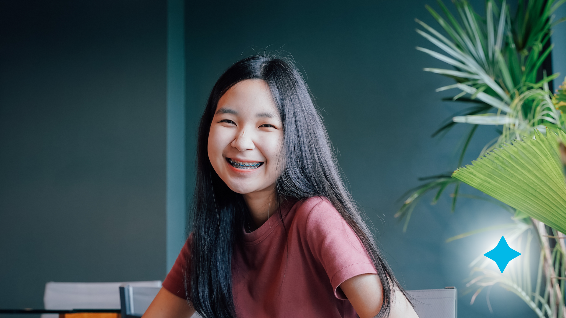 A young woman with braces is smiling while sitting at a table.