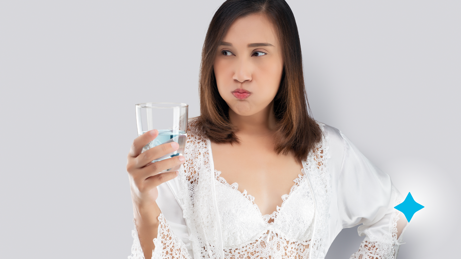 A woman is holding a glass of mouthwash in her hand.