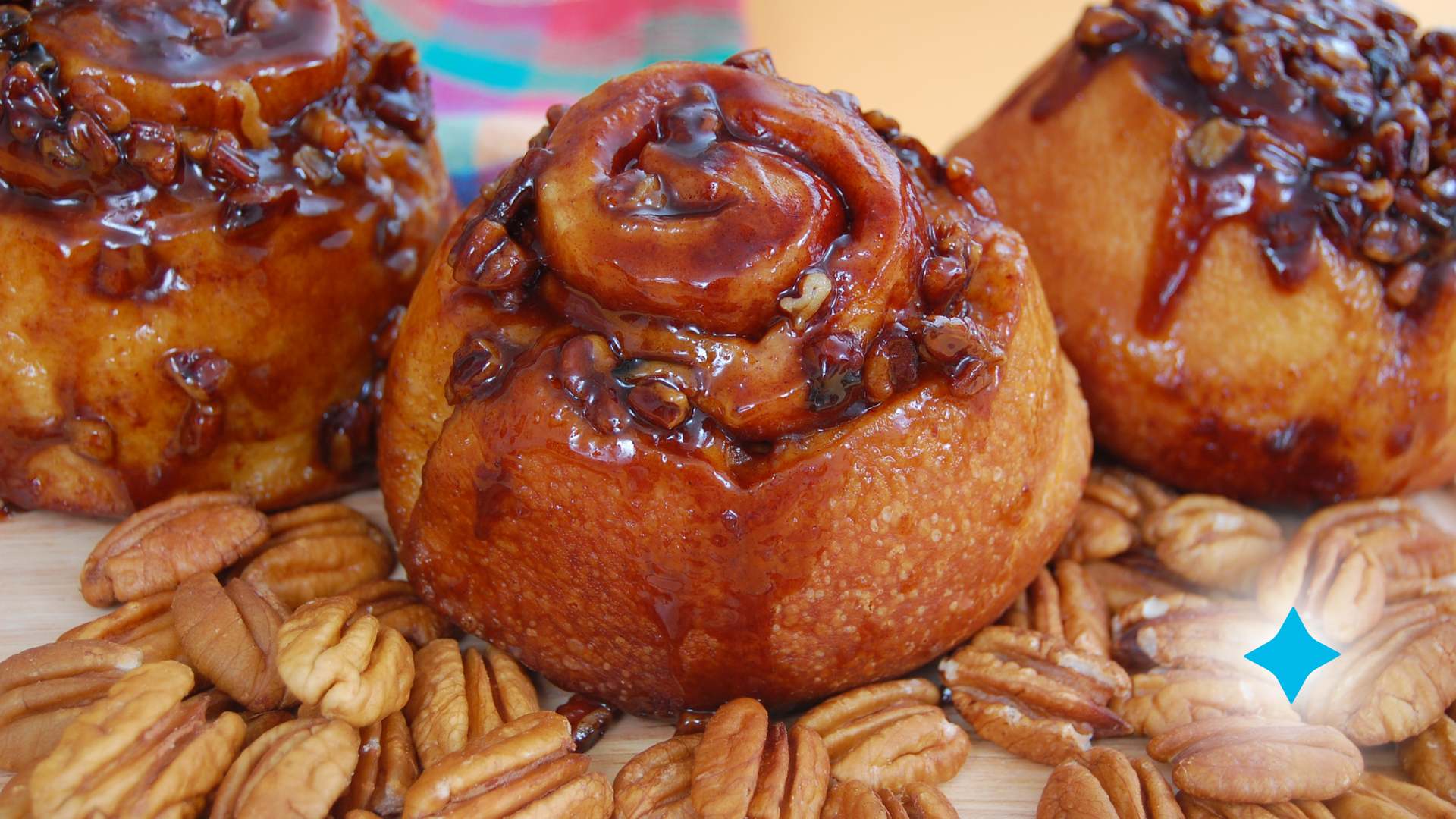 Three cinnamon rolls are sitting on top of a pile of pecans.