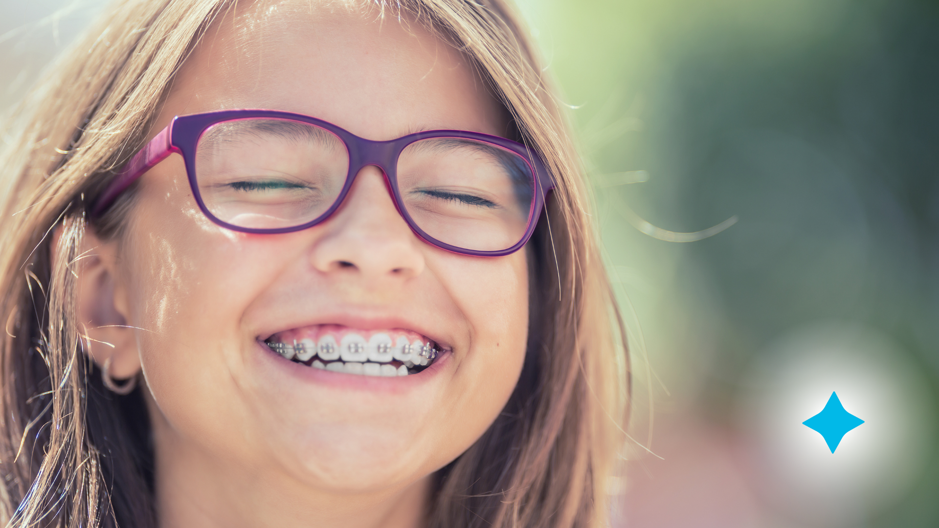 A young girl wearing glasses and braces is smiling.