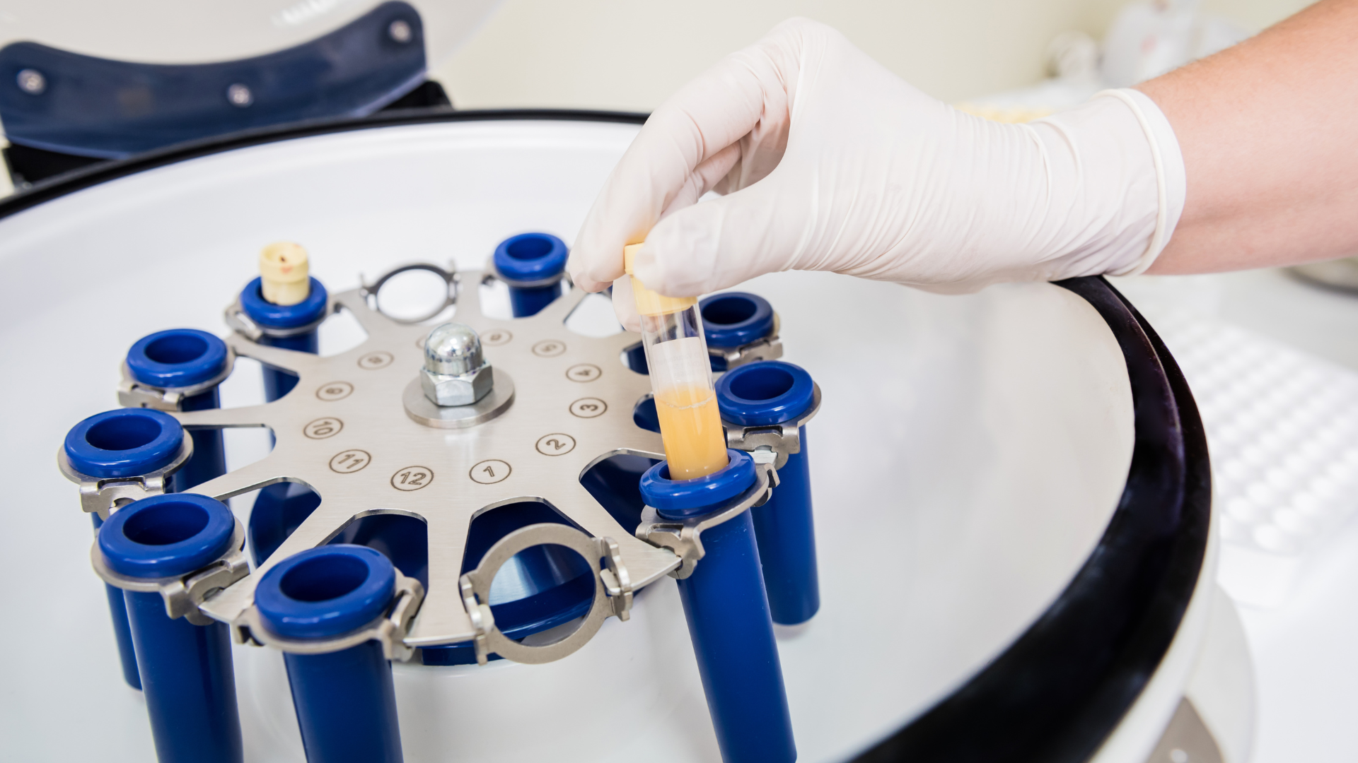 A person is putting a tube into a centrifuge.