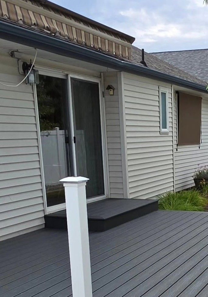 Back deck with gray siding, sliding glass door, and white post railing.