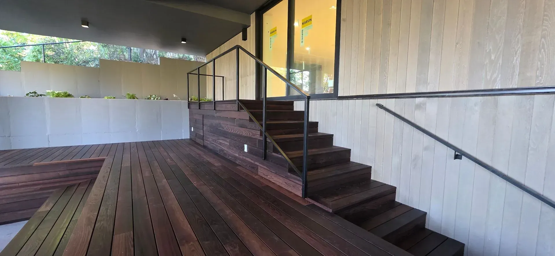 Modern indoor patio with wooden deck, stairs, white railing, and a bar counter with stools