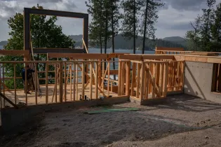 Partially framed wooden deck under construction with a view of trees and a lake beyond