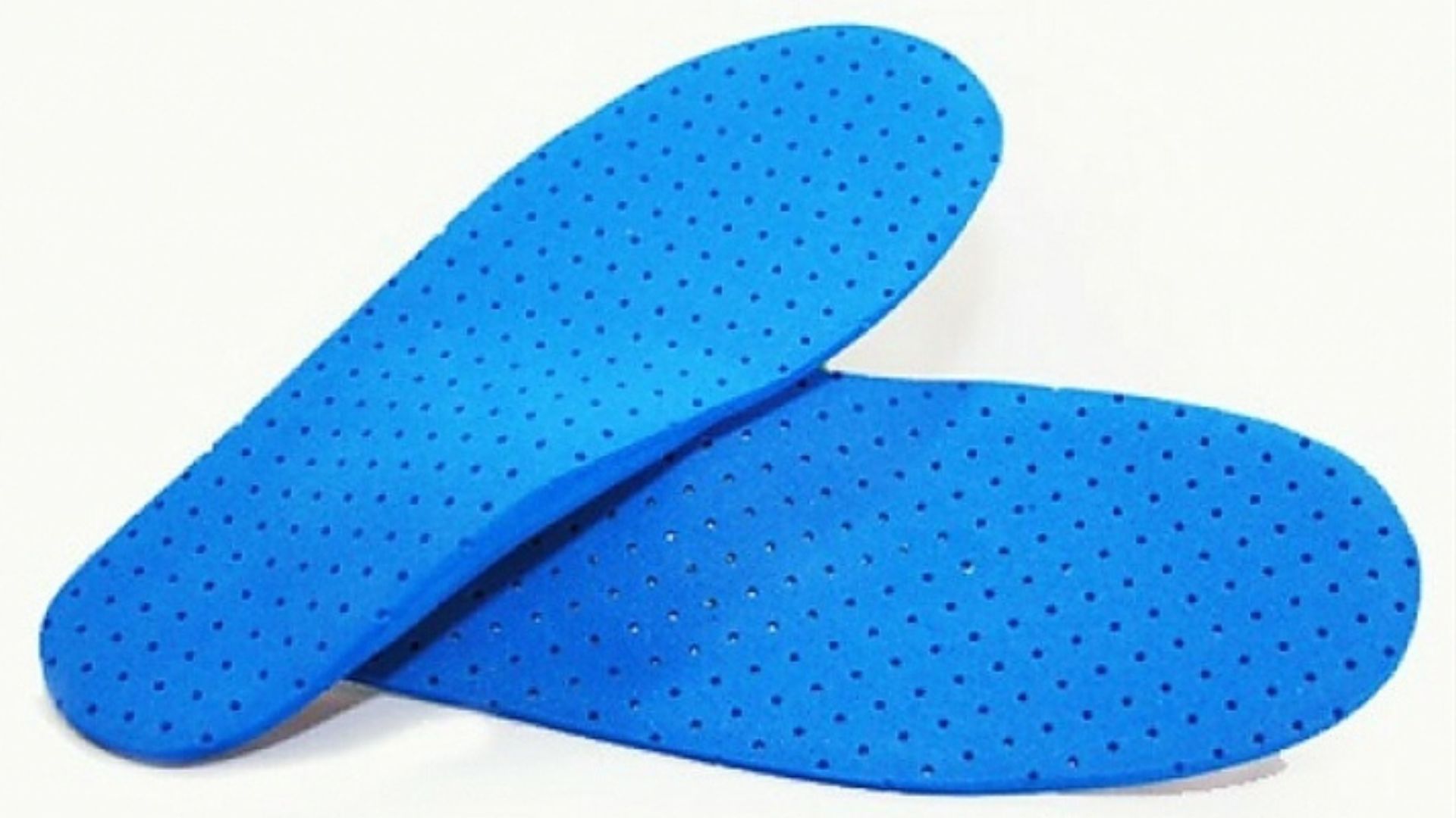Dos plantillas de zapatos de color azul, con agujeros perforados, superpuestas sobre una superficie blanca.