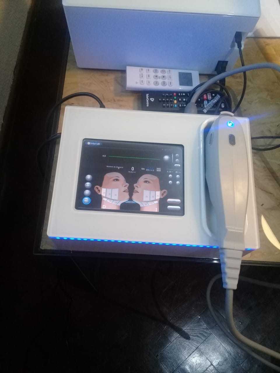 Dispositivo médico con pantalla táctil que muestra un diagrama facial. Colores blanco y azul.