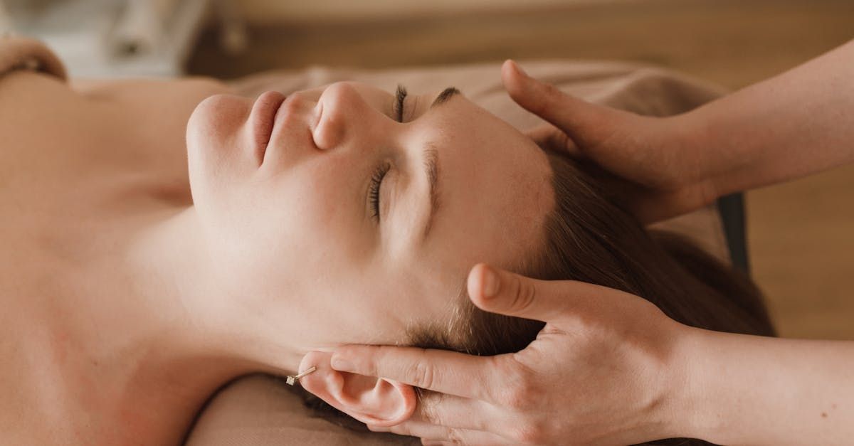 Hands giving a facial massage to a relaxed person lying down