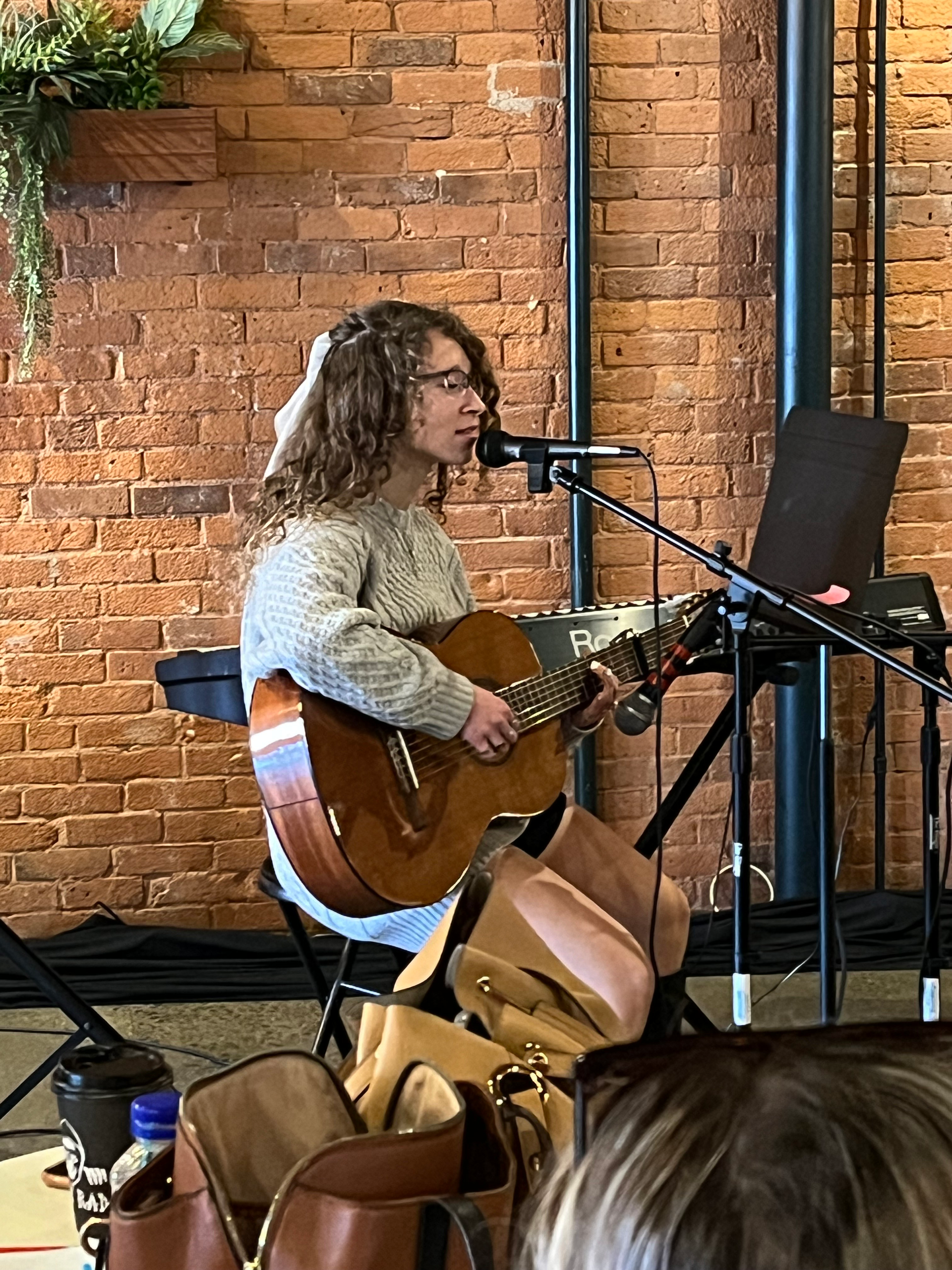 A woman is playing a guitar and singing into a microphone.