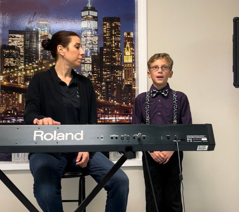 A woman playing a roland keyboard next to a boy