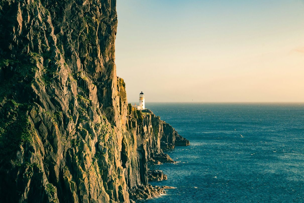 Cliffside lighthouse overlooking the blue ocean at sunset